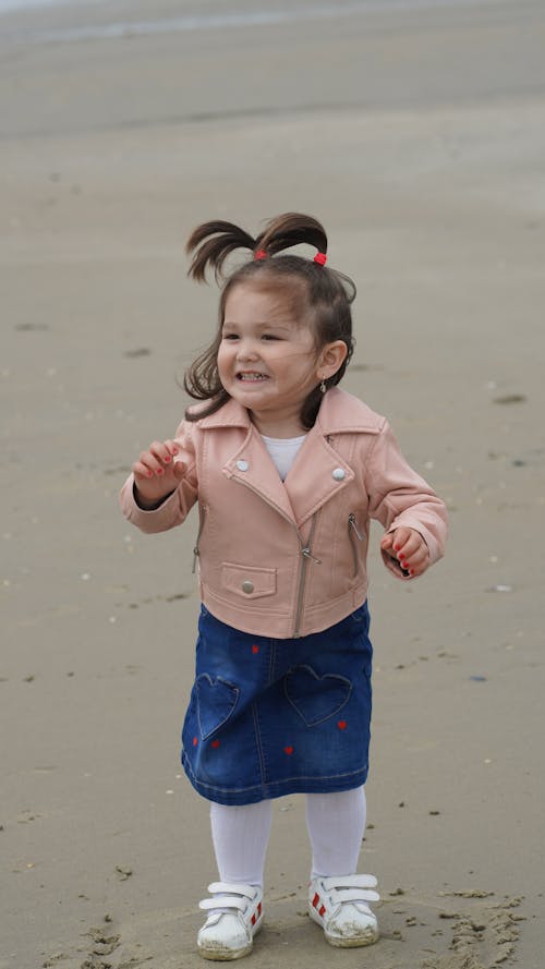 Girl in Pink Zip Up Jacket and Blue Denim Skirt at the Beach