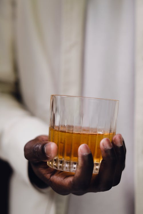 Close-Up Shot of a Person Holding a Glass of Liquor