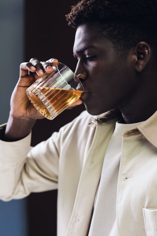 Free A man enjoys a glass of whiskey in an intimate indoor setting, captured in a close-up shot. Stock Photo
