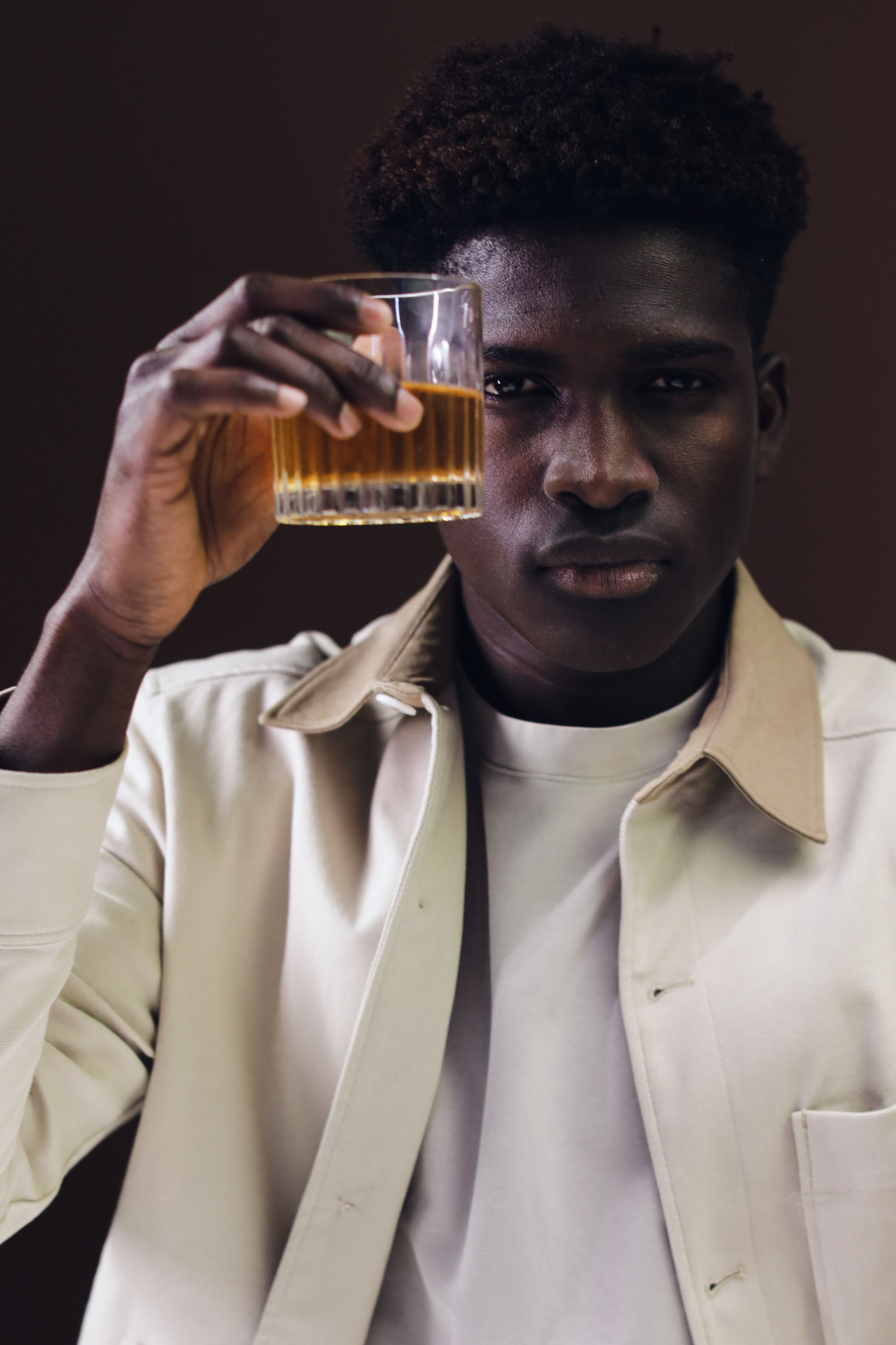 Stylish portrait of an adult man raising a whisky glass indoors.