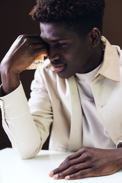 Free A stylish man enjoying a quiet moment with an alcoholic beverage indoors. Stock Photo