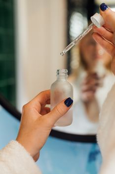 A detailed view of hands using a dropper with a cosmetic bottle, ideal for beauty product promotion.