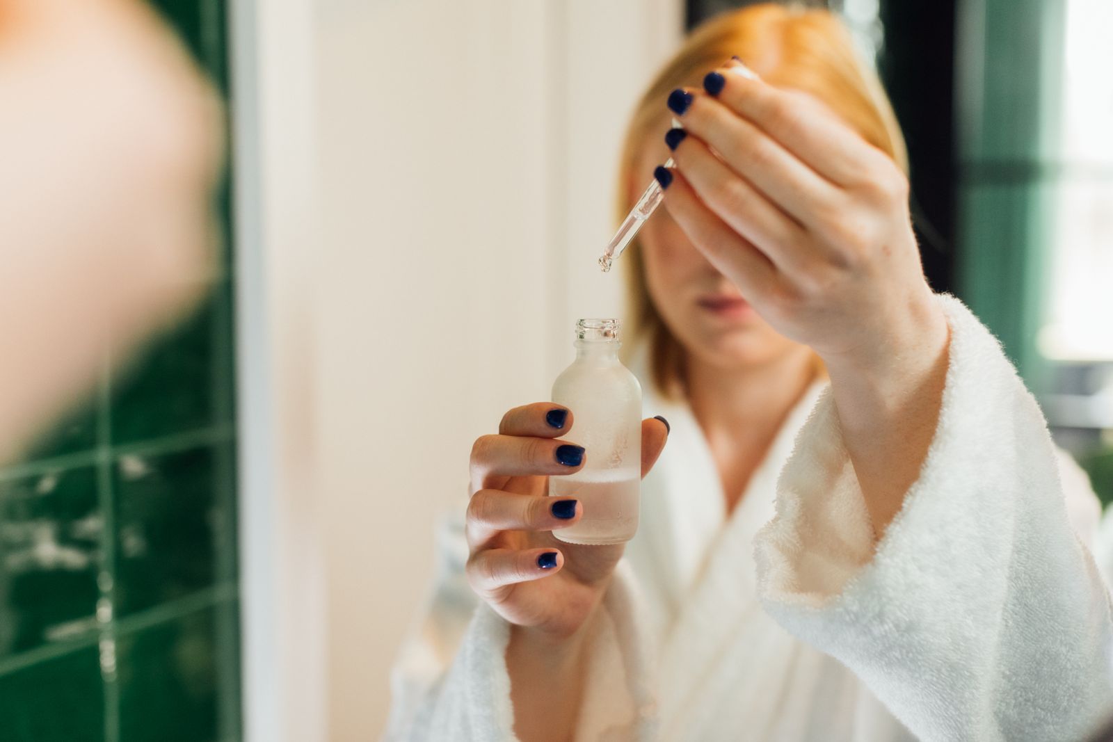 Reflection of a woman holding a serum bottle.