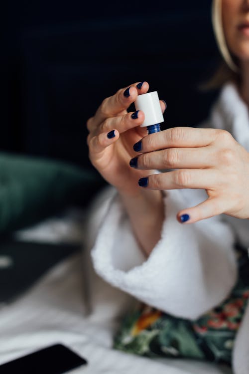Free A Woman Holding a Bottle of Nail Polish Stock Photo