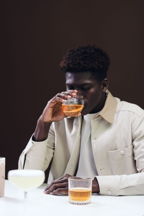 Free Adult man sipping whiskey in a glass on a table with drinks inside. Stock Photo