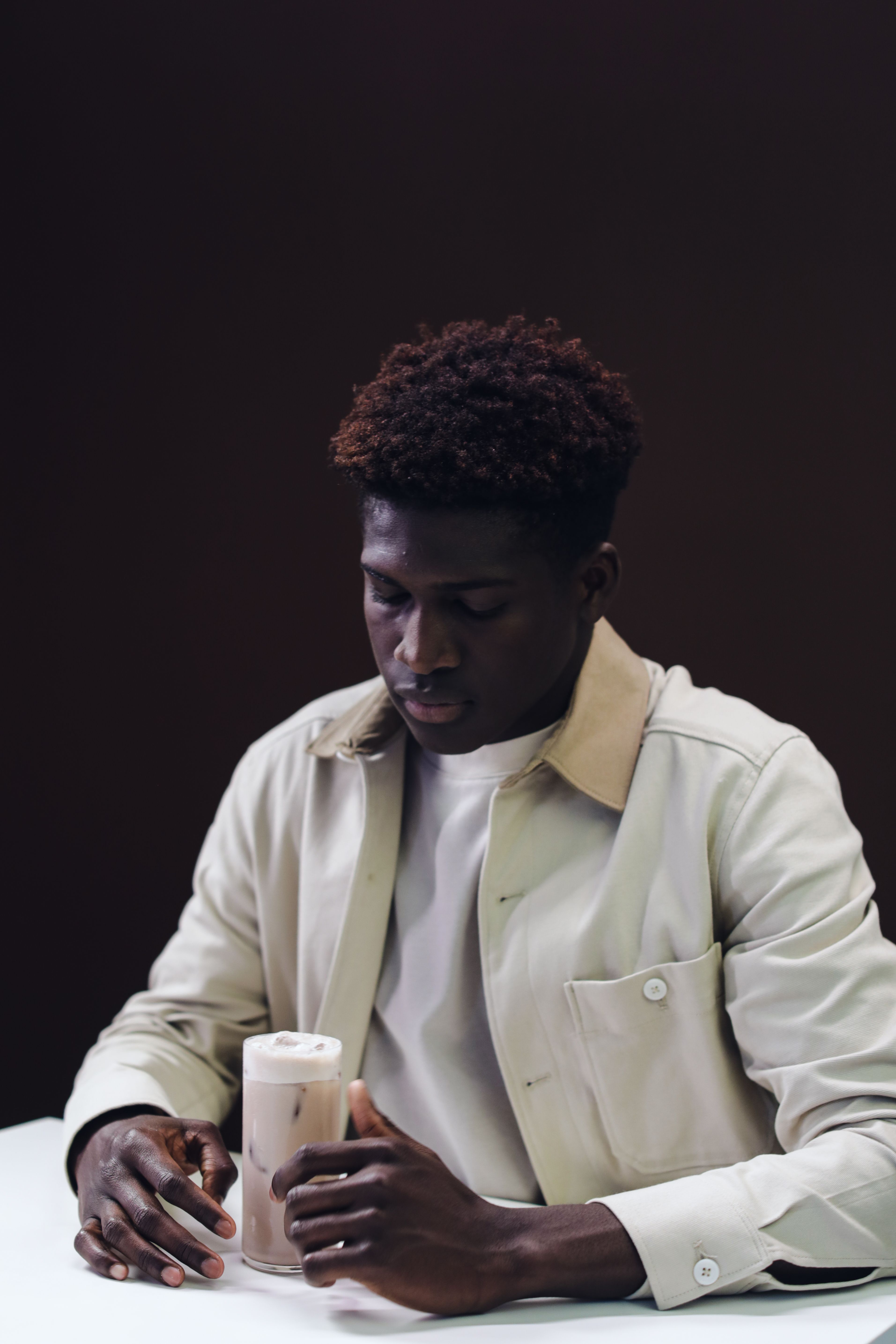 A fashionable man with afro hair enjoys a drink in a modern setting.