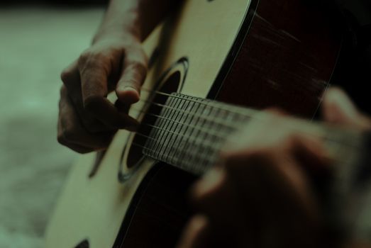 Detailed view of hands strumming an acoustic guitar, highlighting musical expression.