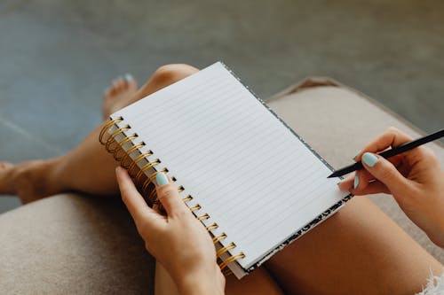 Woman Holding a Spiral Notebook and Pen