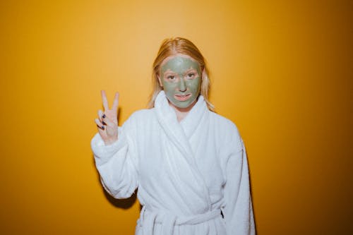 Free Woman in a Bathrobe with Facial Cream Doing a Peace Sign Stock Photo