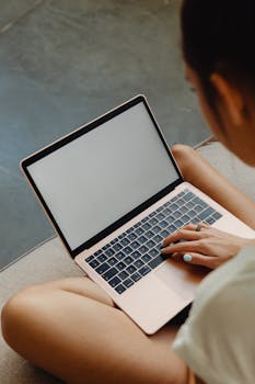 A woman typing on a laptop while seated, viewed from above. Perfect for technology and lifestyle themes.