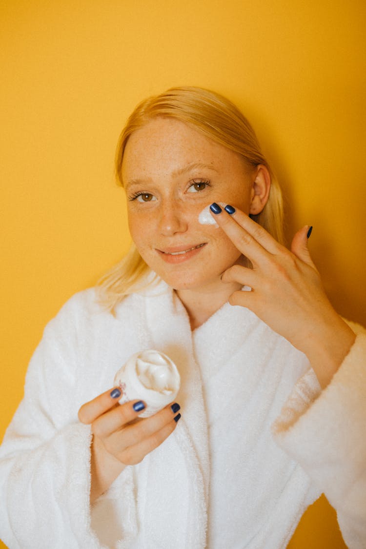 Woman Applying White Cream On Her Face