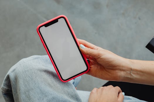 A close-up of a hand holding a smartphone with a blank screen, ideal for mockups.