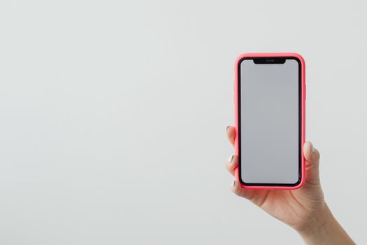 A hand holding a smartphone with a red case against a clean white background, ideal for tech concepts.