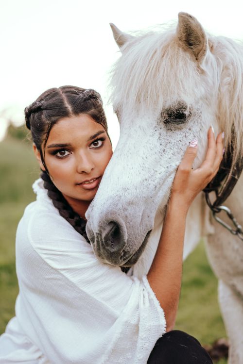 Free A captivating portrait of a woman embracing a white horse, highlighting a serene bond in an outdoor setting. Stock Photo