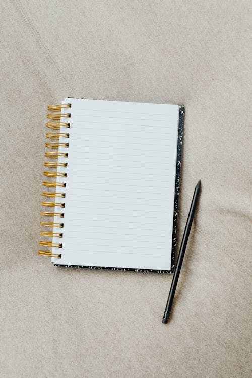 Notebook and Pencil on Beige Surface