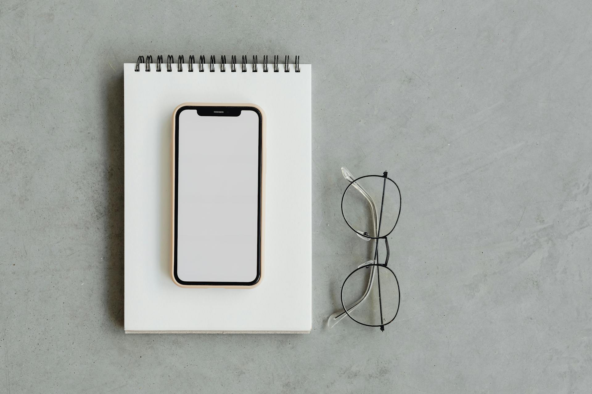 A Mobile Phone on Top of a Notepad