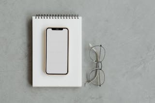 A Mobile Phone on Top of a Notepad