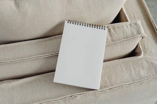 A blank spiral notepad placed on a beige sofa, perfect for mockup or design presentations.