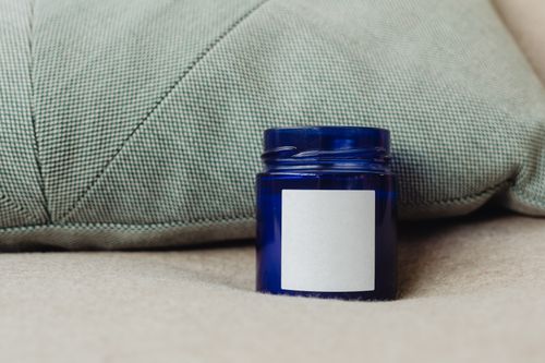 Free A blue container with a blank label, perfect for product mockups, against a cozy cushion backdrop. Stock Photo