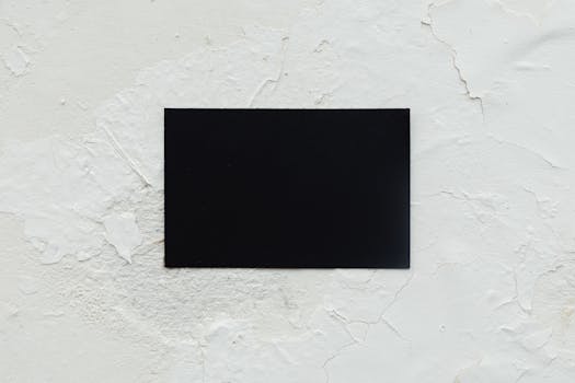 A blank black business card placed on a rough white textured surface, ideal for mockup use.