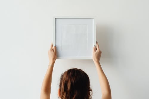 Photo of a Person Hanging an Empty Picture Frame