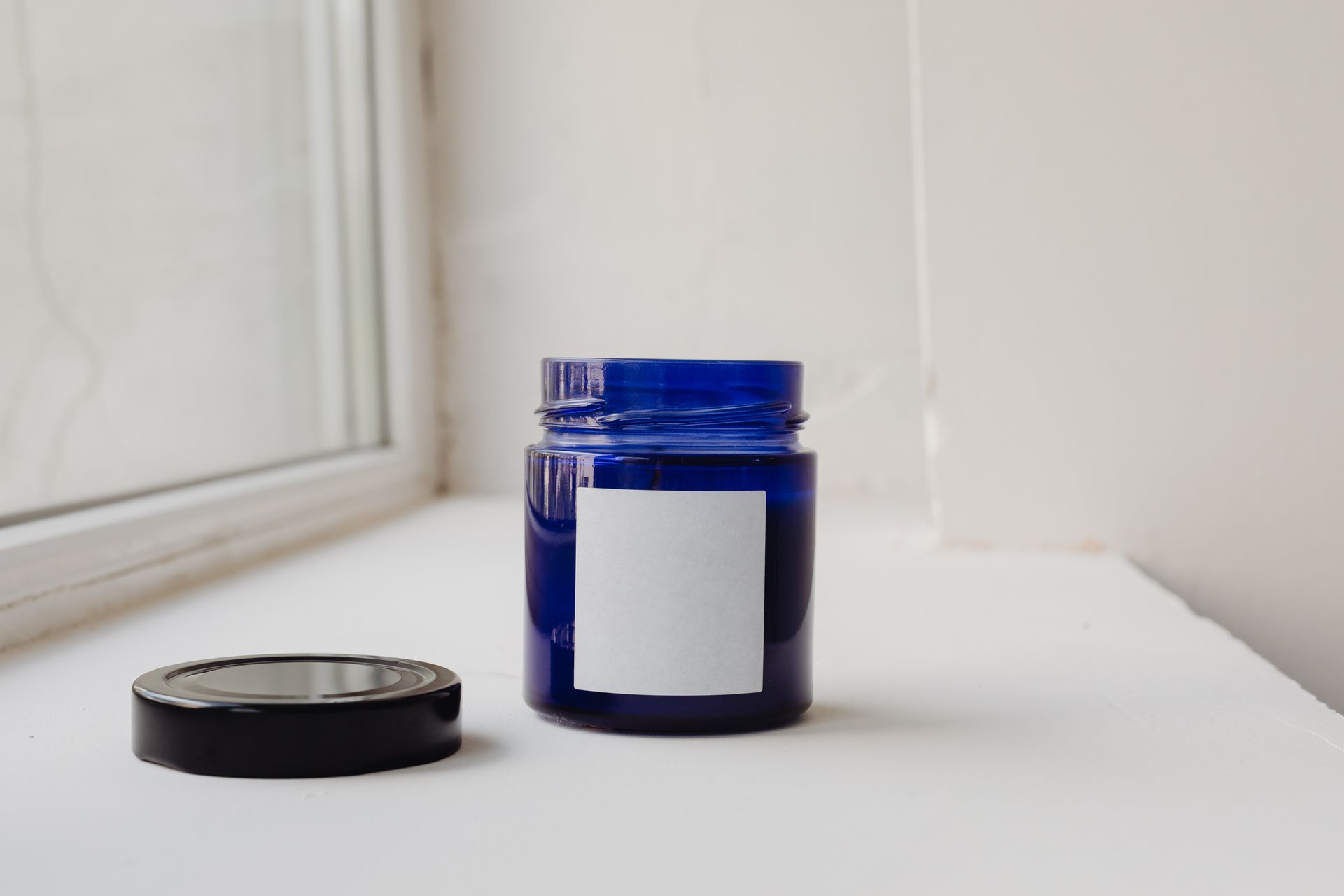 Minimalist shot of a blue glass jar with a blank label, perfect for branding or packaging concepts.
