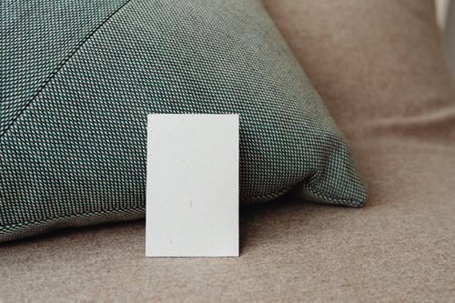 Free Stylish close-up mockup of a white card against a textured pillow background, offering ample copy space. Stock Photo