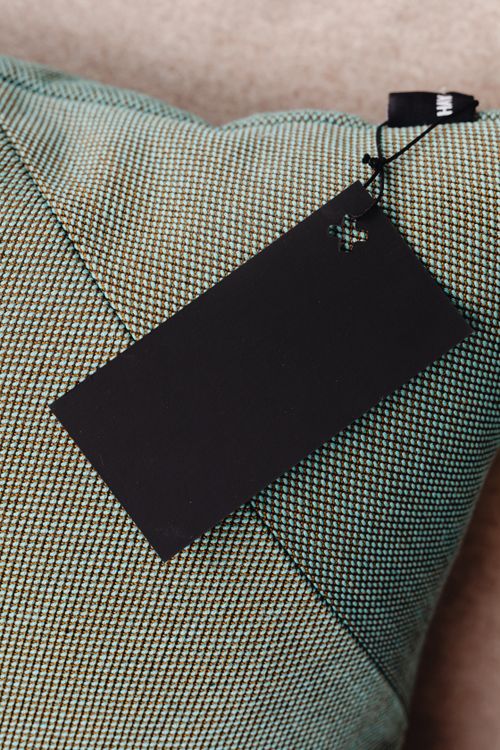 Free Close-up of a cushion with a blank black tag, ideal for your mockup designs. Stock Photo