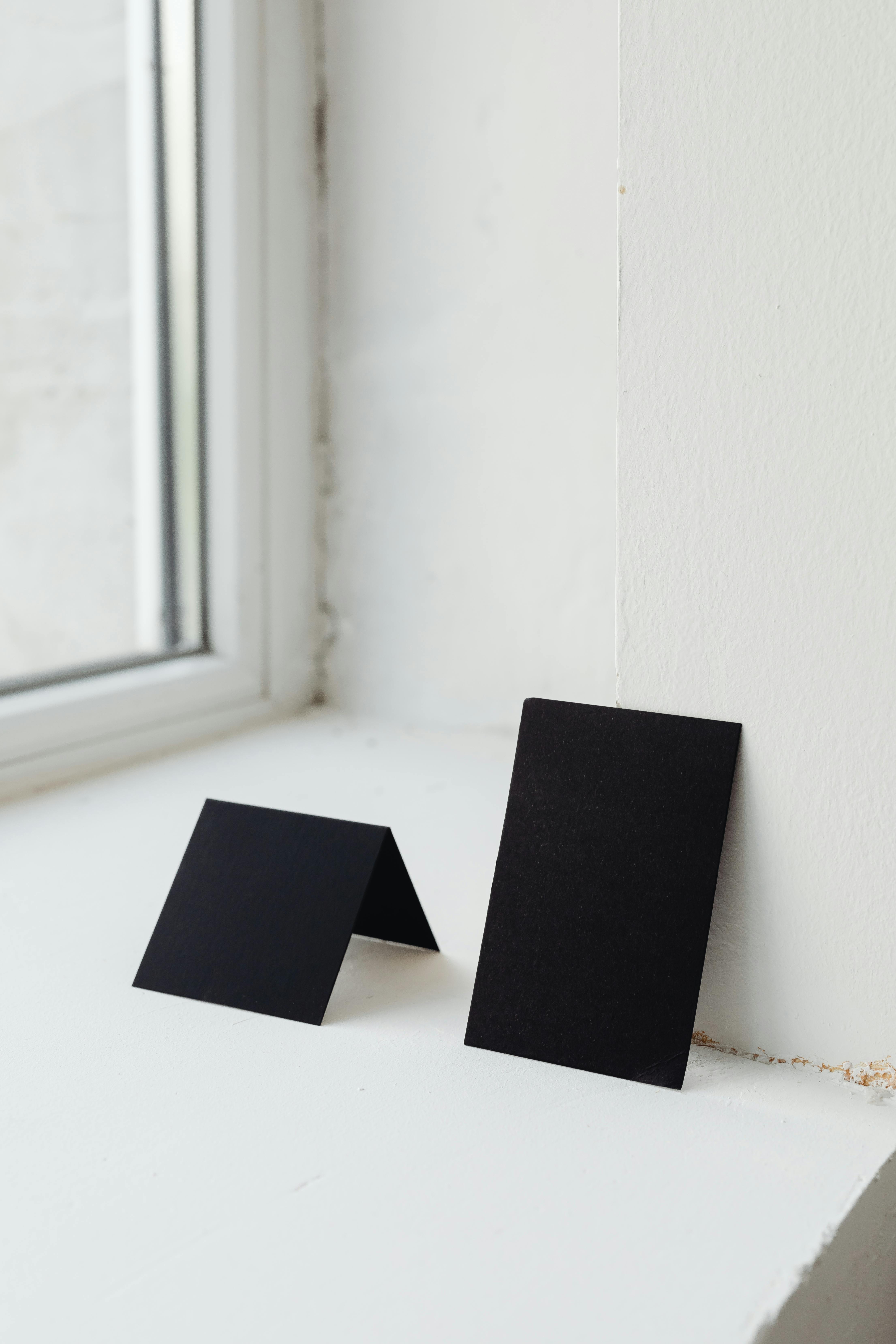 Simple minimalist black card mockup set on a windowsill with natural light, ideal for design presentations.