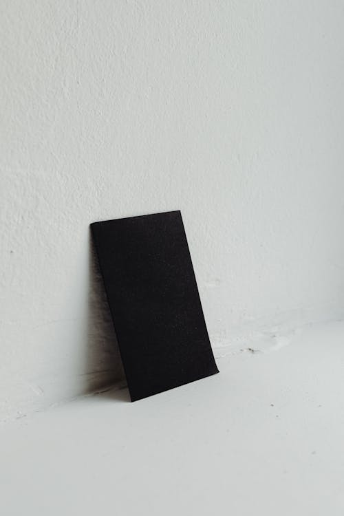 Black Paper Leaning on White Wall