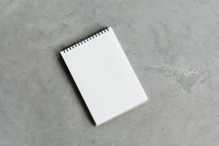 Empty Spiral Note Pad On Concrete Floor