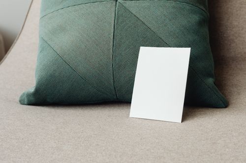Free A minimalist mockup featuring a blank white card against a textured green pillow. Stock Photo