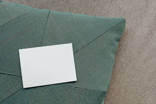 A clean, white business card resting on a textured green cushion, perfect for showcasing branding.