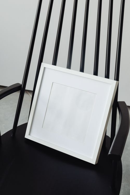 Free Simple black chair with a blank white picture frame, ideal for minimalistic mockups. Stock Photo