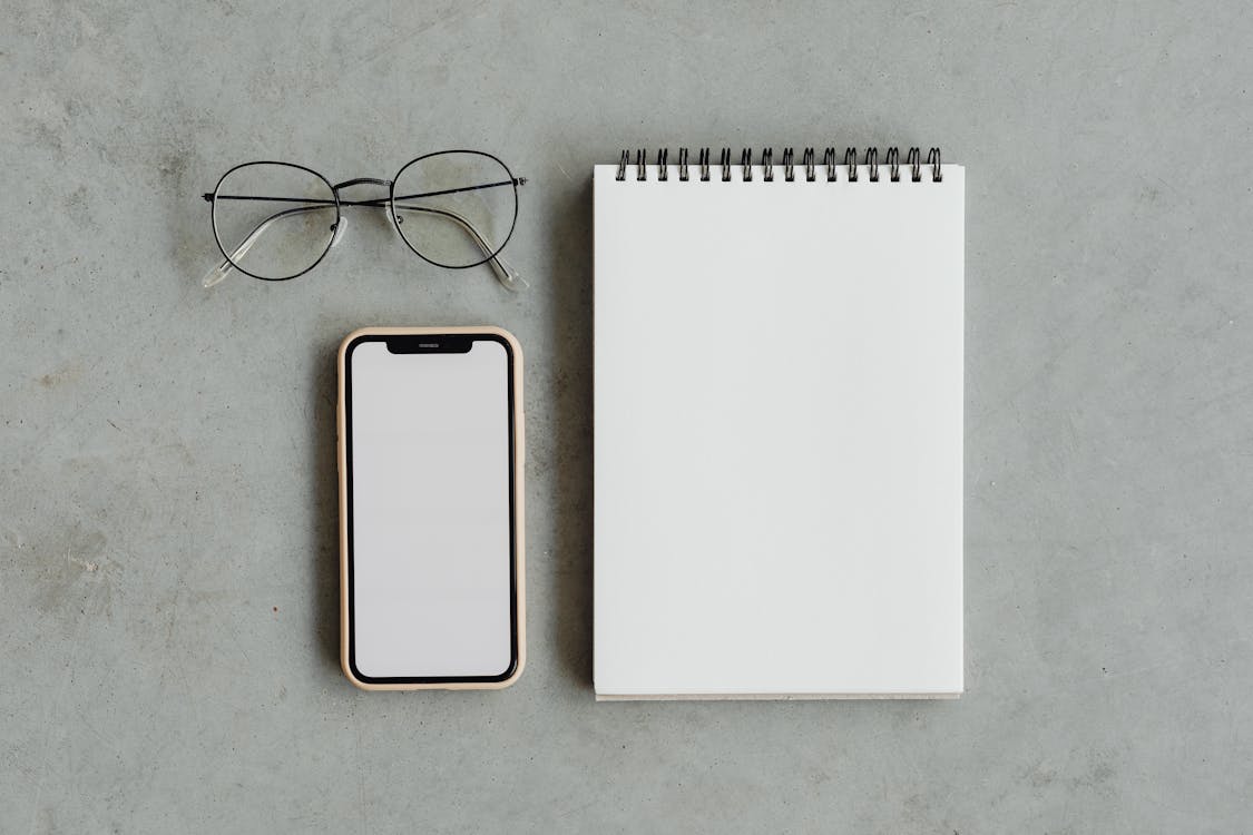 Blank Notepad and a Smartphone with White Screen