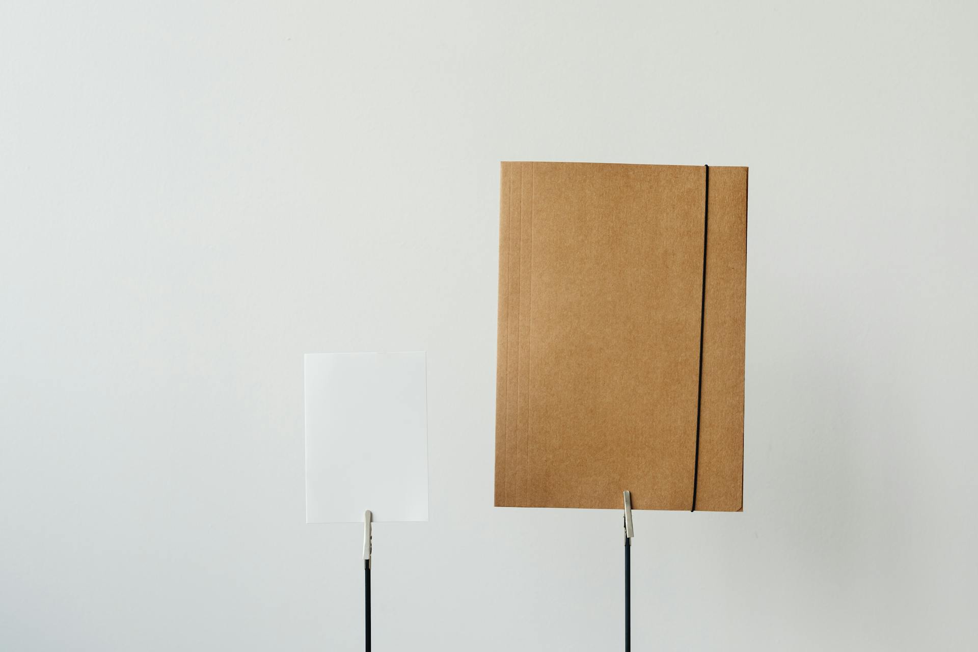 Simple minimalist office setup featuring a paper and brown folder on a white background.