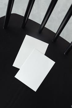 Two blank sheets of paper rest on a black chair providing ample copy space.