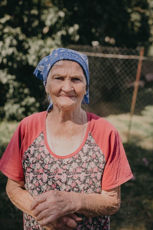 Free Elderly woman with a headscarf enjoying a sunny day in her garden. Stock Photo