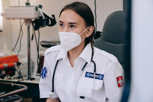 A female paramedic wearing a face mask with a stethoscope in a medical room, focused on healthcare delivery.