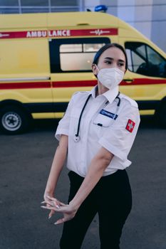 Female paramedic in uniform with stethoscope standing by an ambulance outdoors.
