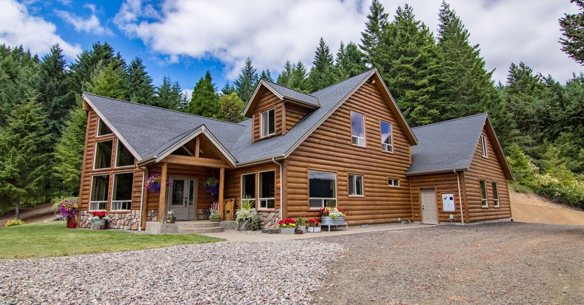 A picturesque log cabin surrounded by a lush forest under a vibrant blue sky.