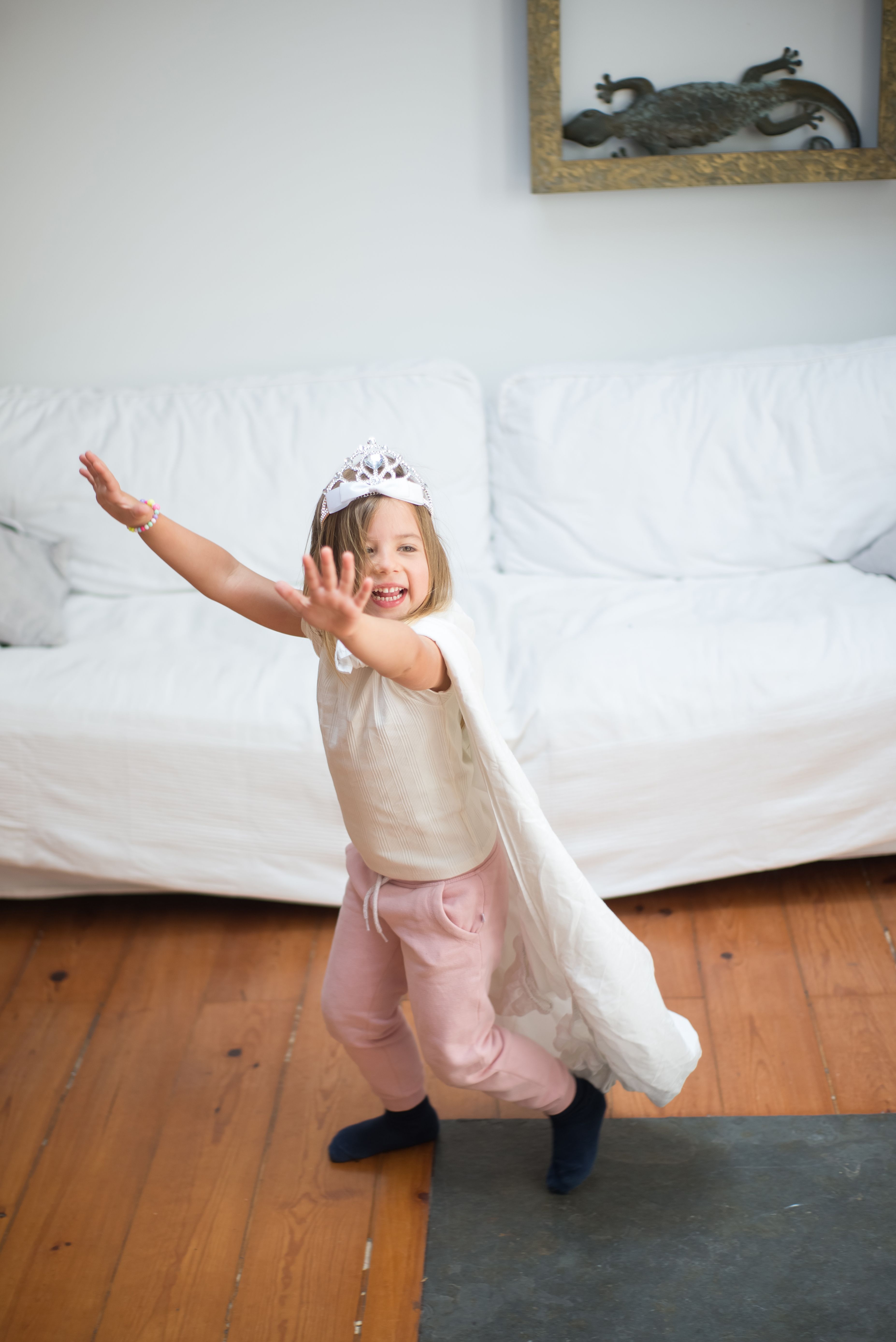 Happy child in a crown and cape enjoying pretend play indoors.