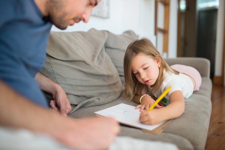 Photo Of A Girl Drawing While Lying On A Sofa