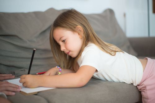 Free A young girl focused on drawing with pencils on a comfortable couch at home. Stock Photo