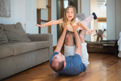 Man Lying on the Floor While Lifting a Girl