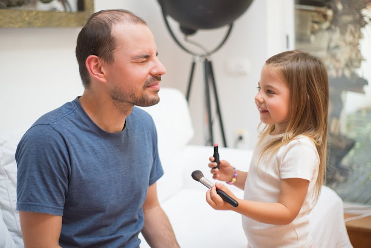 Photo Of A Child Putting Makeup On Her Father