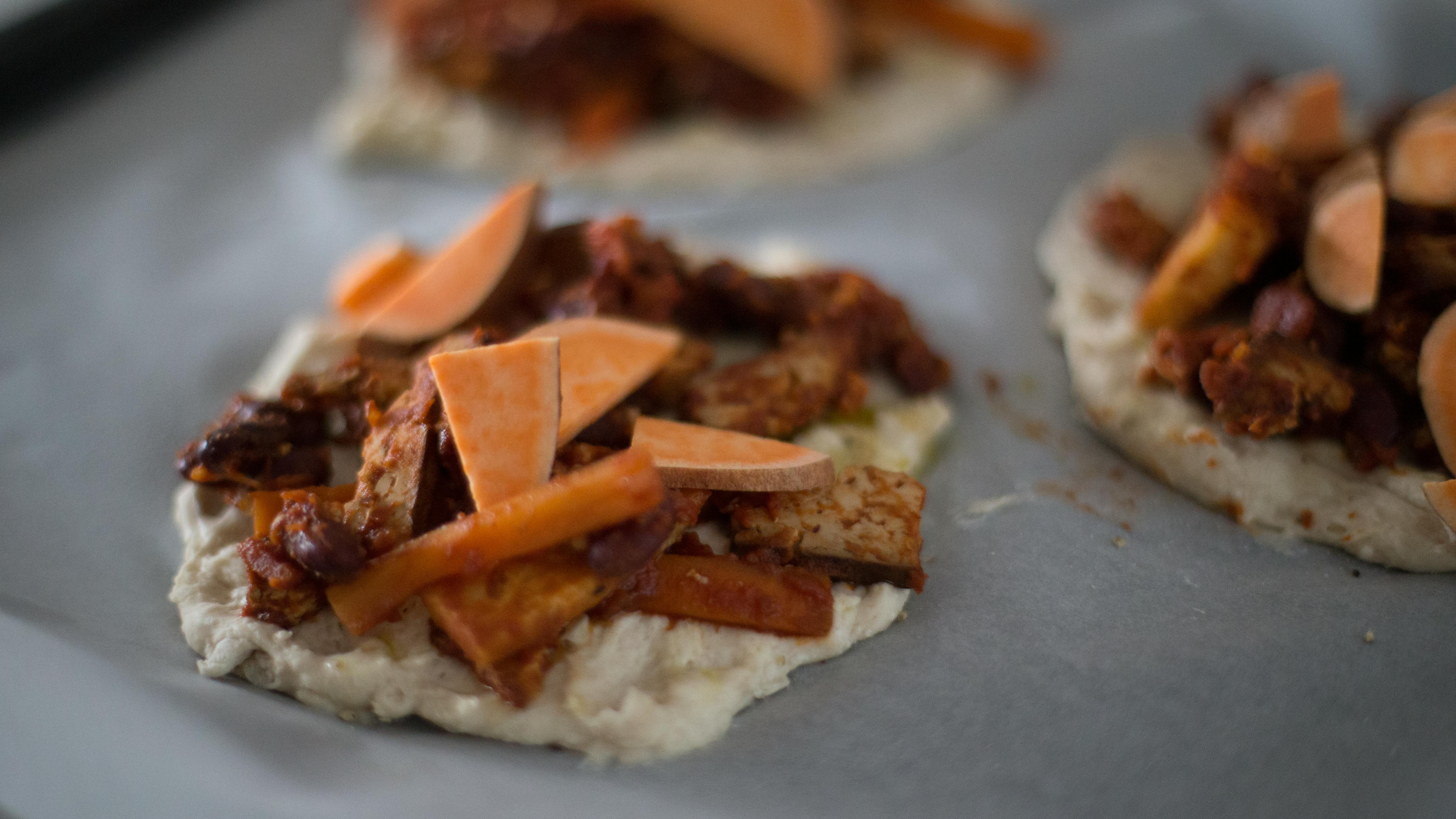 Close-up of homemade flatbreads with sweet potatoes and seasoned vegetables.