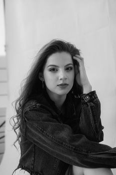 Black and white portrait of a woman wearing a denim jacket, posing thoughtfully.