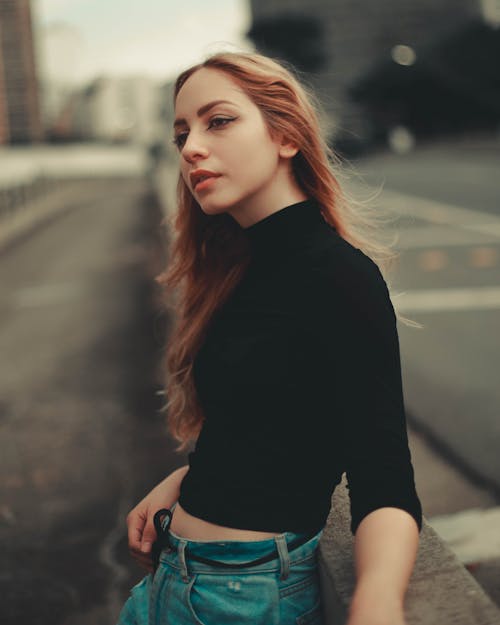 Woman Wearing Black Shirt Standing Against a Concrete Barrier