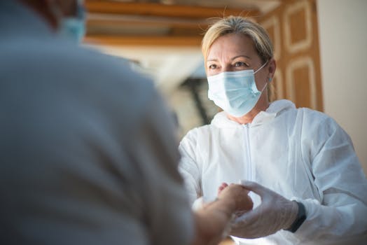 A healthcare worker in protective gear providing care indoors. Focused face with surgical mask.